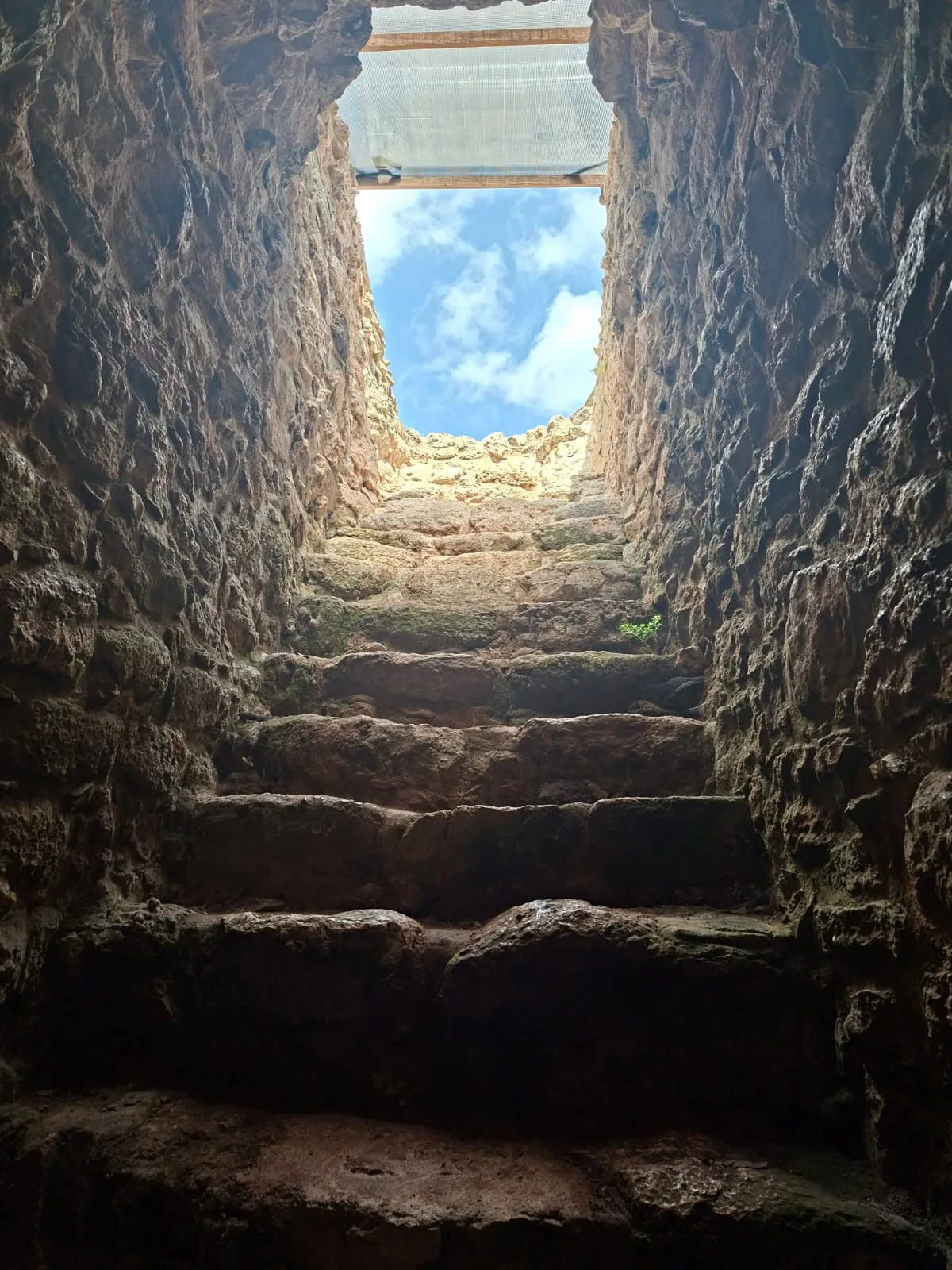 Escalones de piedra que suben hacia el cielo abierto