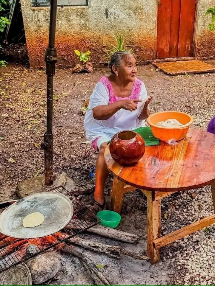 Una señora de la comunidad echando tortillas junto al fogón