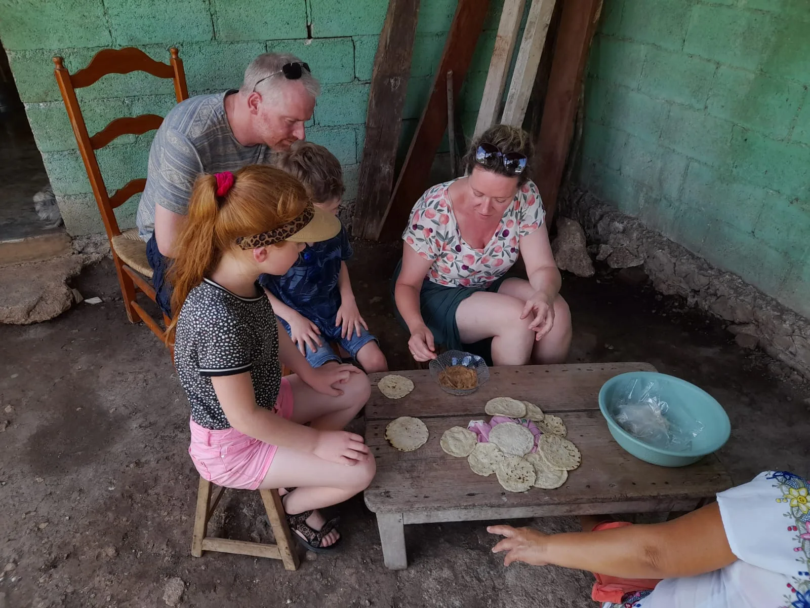Visitantes formando tortillas a mano en la mesa baja